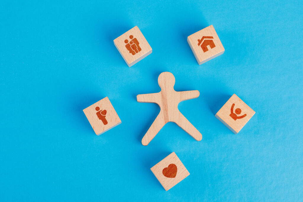Family concept with icons on wooden cubes, human figure on blue background flat lay.